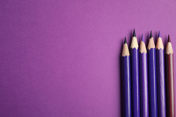 Flat lay composition with color pencils on purple background. Space for text