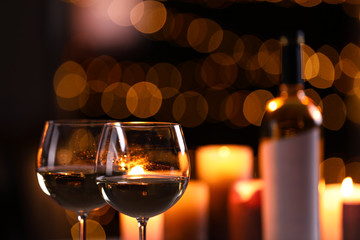 Glasses of wine and blurred view of burning candles on background