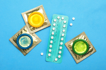 Condoms and birth control pills on light blue background, flat lay. Safe sex concept