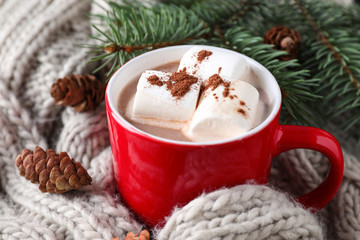 Obraz na płótnie Canvas Cup of tasty cocoa with marshmallows on knitted cloth, closeup