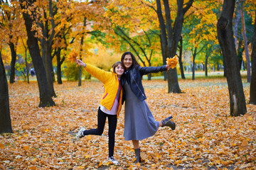 woman having fun with autumn leaves in city park, outdoor portrait