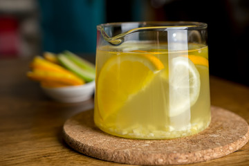 Hot lemon, ginger and apple tea with spices in a glass teapot. Health fresh fruit drink. Enjoying hot beverage in cold winter evening. Selective focus