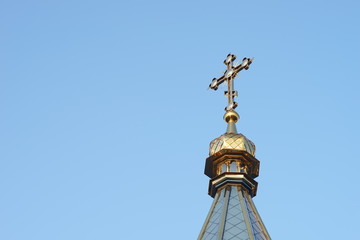 Fototapeta na wymiar the upper part of the roof of the Orthodox Church with a cross against a blue cloudless sky.