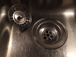 Shiny metal sink with a plug, close. Silver color. Scratch the surface.