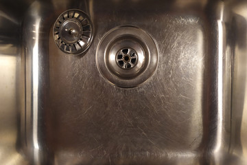 Shiny metal sink with a plug. Silver color. Scratch the surface. The view from the top.
