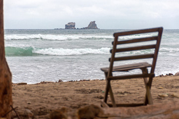 Old wooden beach chair facing the ocean, on an overcast and gloomy morning, Ayampe, Manabi, Ecuador