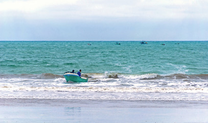 Fototapeta na wymiar Fishermen in a small boat in the ocean coming back to land, Puerto Cayo, Manabi, Ecuador