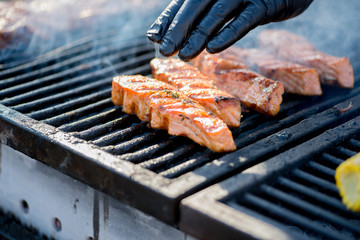 Cooking BBQ Fish.Gloved hands turn pieces of fish on the grill.