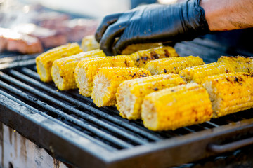 BBQ corn on an open grilles fire.Hand in glove overtakes pumpkin corn
