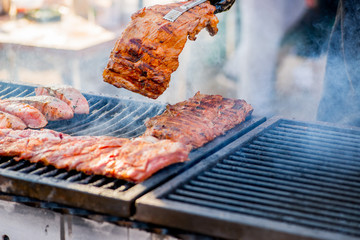 BBQ ribs. Hands in gloves overtake fried ribs on the grill