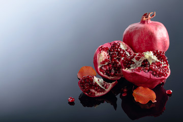 Ripe pomegranate fruits on a black reflective background.