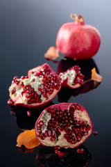 Obraz na płótnie Canvas Ripe pomegranate fruits on a black reflective background.
