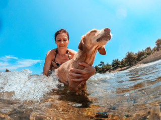 Woman and her dog at the beach swimming in the sea