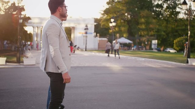 Two elegant businessmen riding hoverboard in city park on sunny day, slow motion