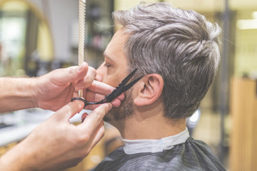 Man in barber chair, hairdresser styling his hair.