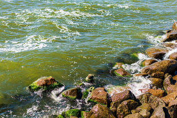 Close-up of a breakwater made of giant boulders, Baltic sea, in Palanga, Lithuania, Europe. Green Baltic sea water breaking on the stone groyne.