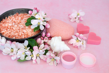 Obraz na płótnie Canvas Skin care beauty treatment with exfoliation mineral salts, cleansing products and apple blossom flowers on pink background.