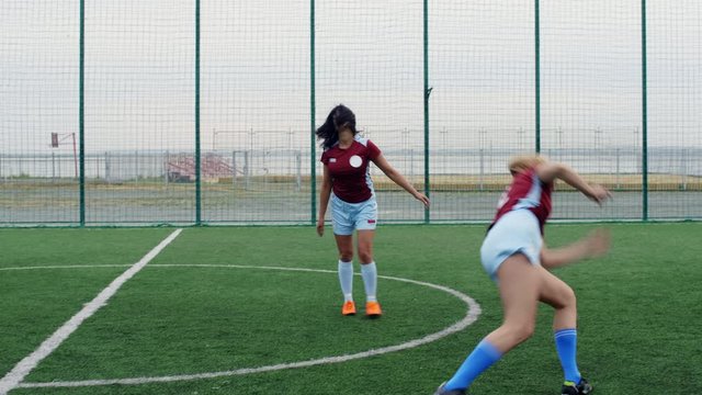 Two smiling soccer women celebrating win, doing wheel on outdoor arena and hugging