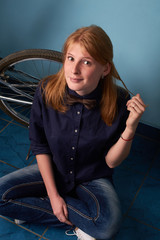 Fototapeta na wymiar pretty girl sitting on the floor of a bike shop near a bike
