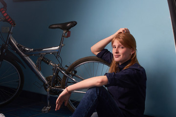 Fototapeta na wymiar pretty girl sitting on the floor of a bike shop near a bike