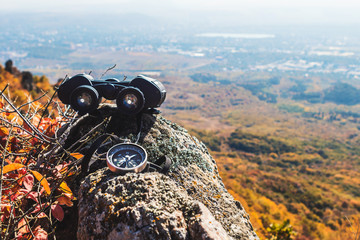 Binoculars and compass lie on a rock, high in the mountains in autumn. © Pyroll