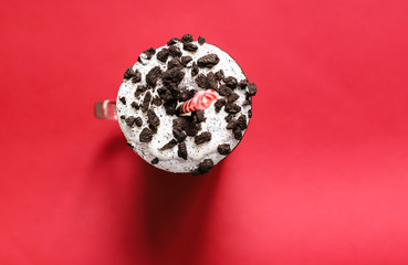 donut with cookie pieces on the cup of milk with the straw, red background. 