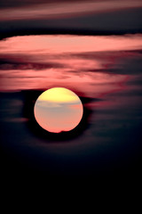 yellow and gray sun with pink clouds on a black sky