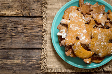 Homemade Decorated Gingerbread Men Cookies for Christmas on a plate on rustic aged wooden table. Flat lay view.