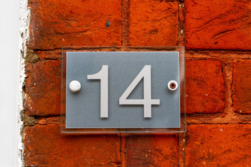 House number 14 on a red brick wall