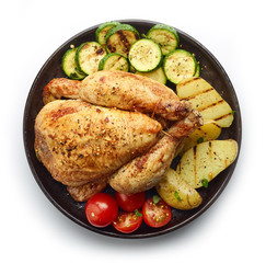 Roasted whole chicken with grilled vegetables on black plate