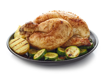 Roasted whole chicken with grilled vegetables on black plate