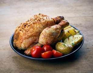 Roasted whole chicken with grilled vegetables on black plate