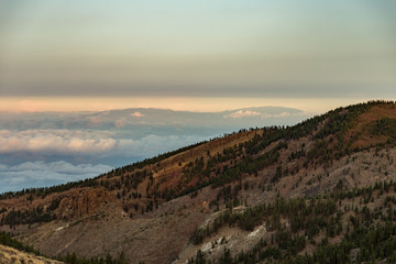 Volcanic landscape of Tenerife with a view at La Palma 100 kilometer away over the ocean. Mountain point above the clouds at clear sunny day. Long focus shot