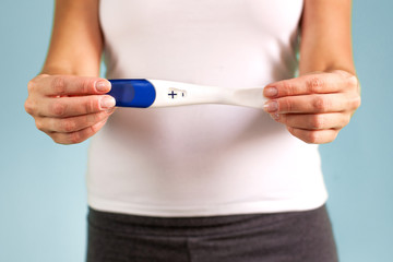 The girl holds in her hand a positive pregnancy test. The beginning of pregnancy. Pregnancy proof. Selective focus.