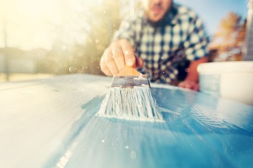 Man with paintbrush in hand and painting on the wooden board