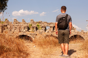 A tourist walks near ancient monuments. Man, sunny day. Training and horizons. Excursions and self-education.