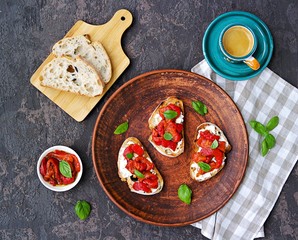 Bruschetta with baked red pepper, cream cheese and fresh basil on a clay plate. Italian Cuisine. Red pepper snacks. Top view, copy space.