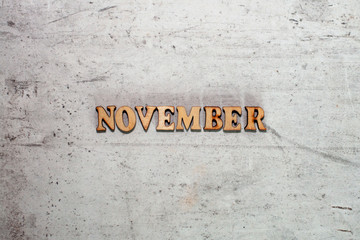 The word November laid out in wooden letters on a light background. Close-up. Summer time years and months of the year.