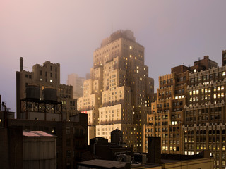 View of vintage New York skyline from rooftop at night in fog.