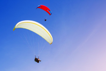 Two paragliders fly in the blue sky. Parachute extreme sport. Paraglayding.