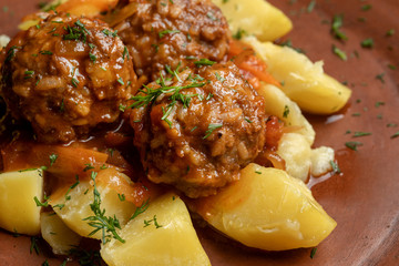 Meatballs with potato wedges on a beautiful clay plate.
