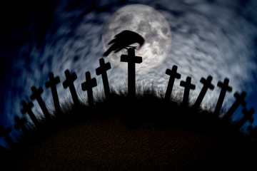 Crow sitting on a cross in moonlight