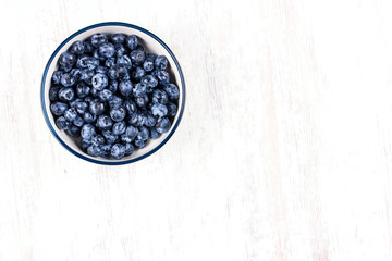 Fresh blueberries in a white bowl on wooden table