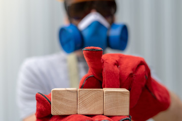 Industrial worker in protective equipments holds wooden cubes and touches virtual button on GUI...