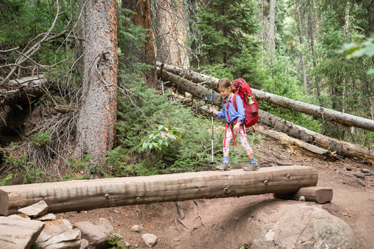 Young girl crossing a log while hiking on a backpacking trip in the Gore Range, Colorado.