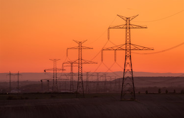 Silhouette electricity pole, electricity pylons technology on sunset time background, Ceske Stredohori, Czechia