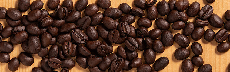 Stack of coffee beans on wooden floor. Panorama.