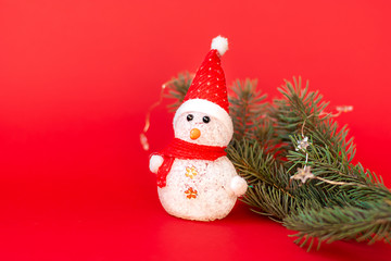 Snowman and fir branch on a red background. Christmas background