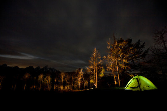 A night shot of an illuminated tent at a campsite overlooking the Teton Range outside of Jackson, Wyoming