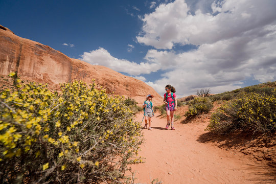Family with young children hiking to Corona Arch, located just west of Moab, Utah.
